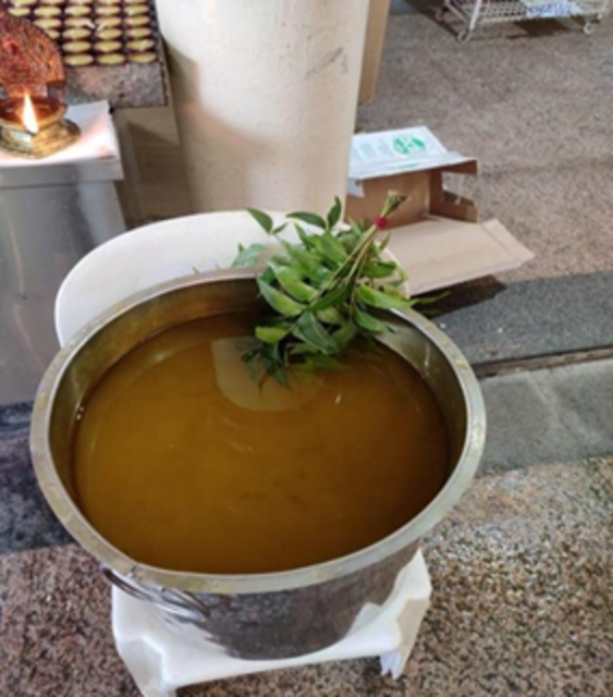 Photo of a pot with turmeric water and neem leaves on a plastic chair.