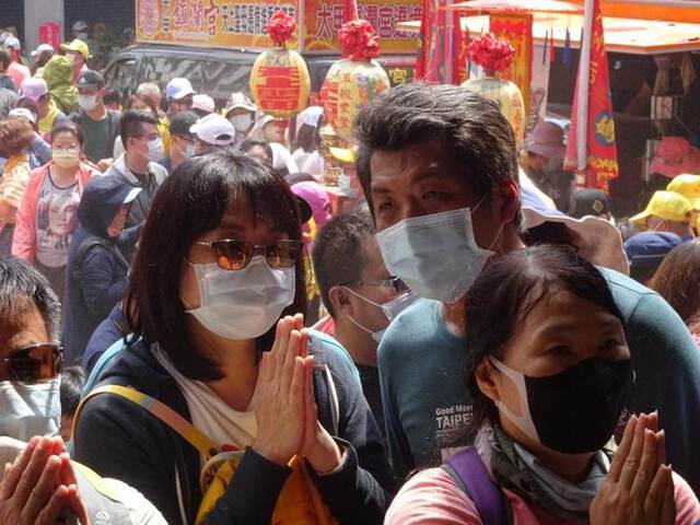 Photo of people wearing masks while praying during Dajia pilgrimage ritual in Taiwan.