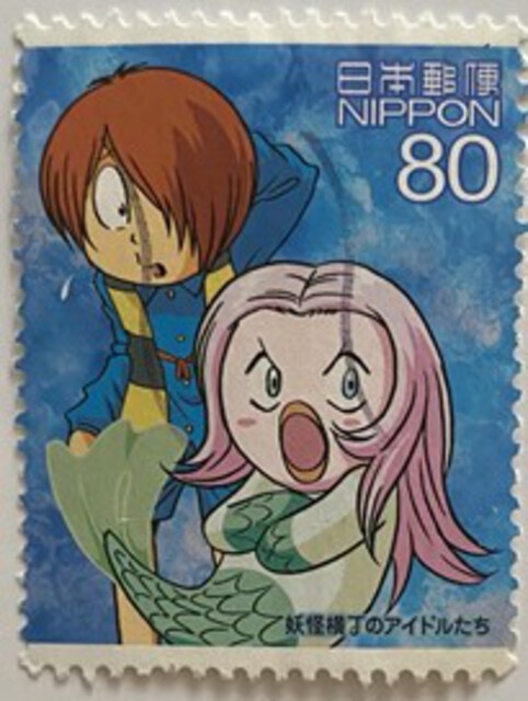 Photo of a stamp showing a person and Amabie Girl (long hair with fish-tail).