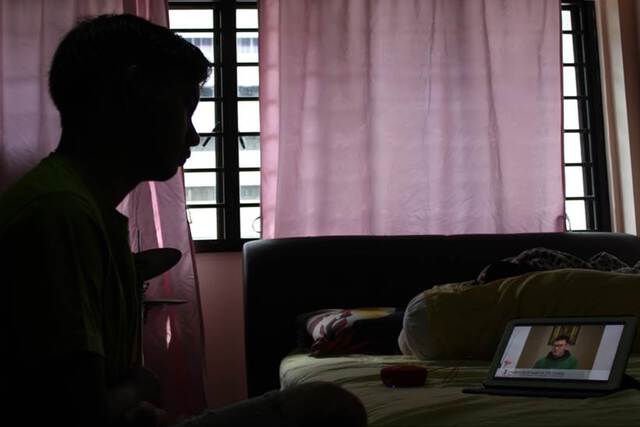 Photo of a man watching mass celebrated online from a tabled placed on his bed.